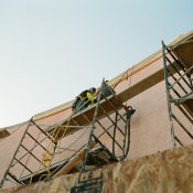 man in yellow shirt climbing on brown concrete building during daytime