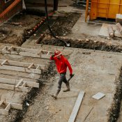 man in red jacket and black pants walking on gray concrete stairs